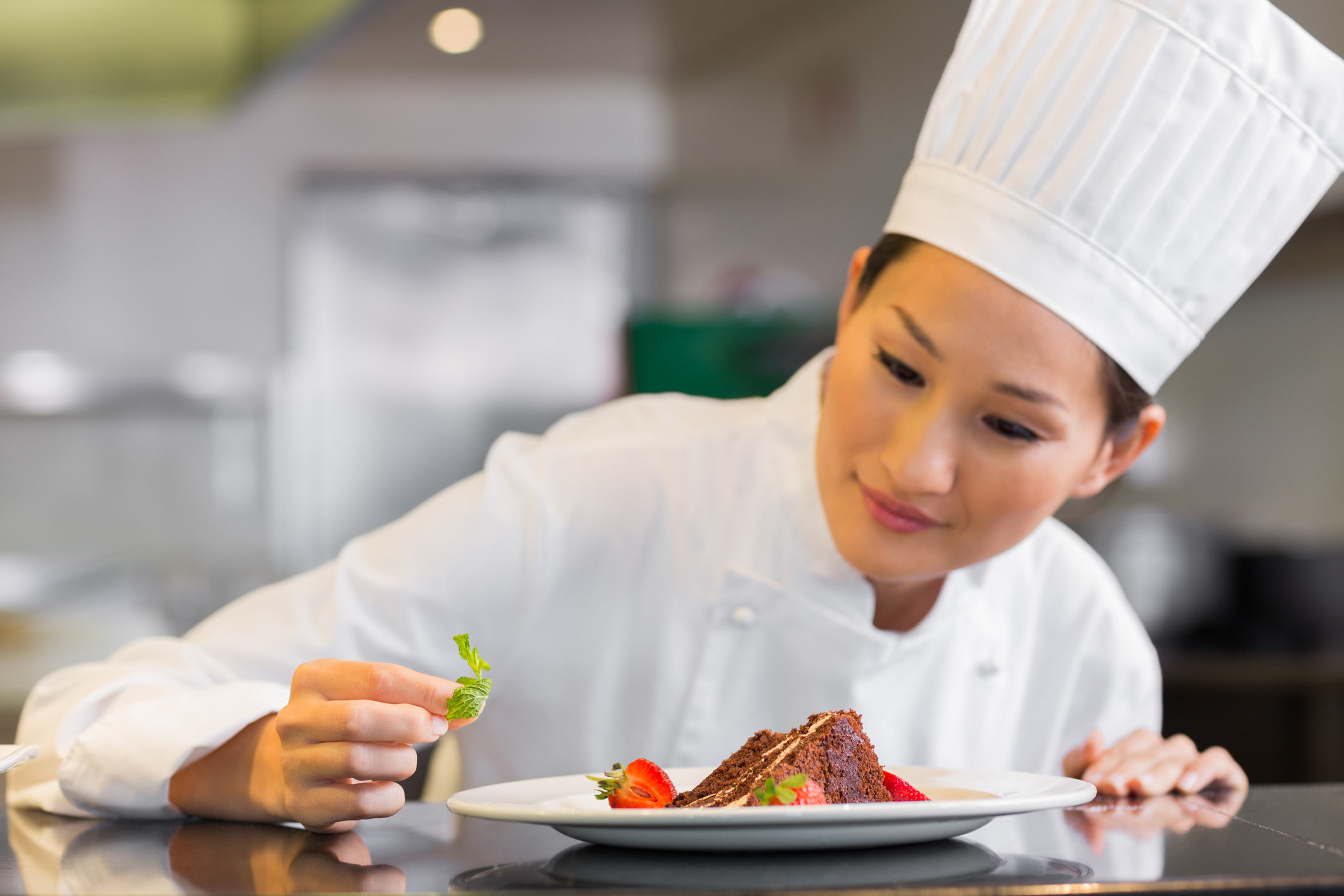 Closeup of a concentrated female chef garnishing food in the kitchen